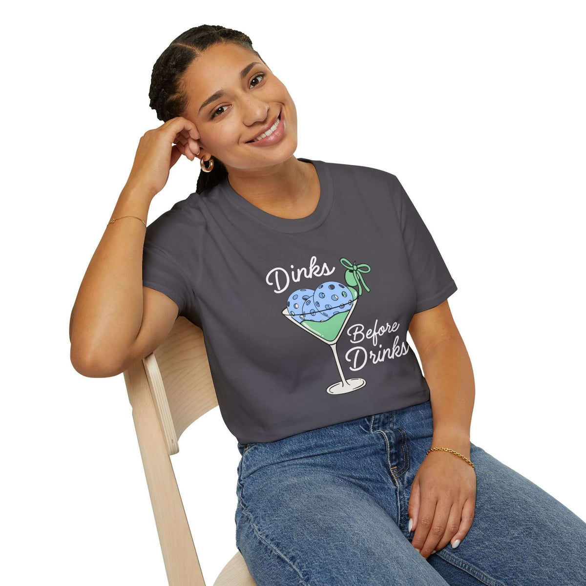 Woman wearing a gray Dinks Before Drinks T Shirt with a martini-glass illustration in colorful design.