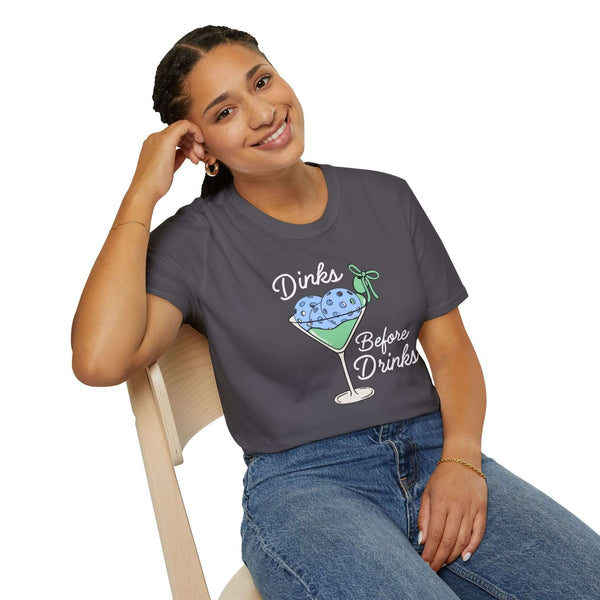 Woman wearing a gray Dinks Before Drinks T Shirt with a martini-glass illustration in colorful design.
