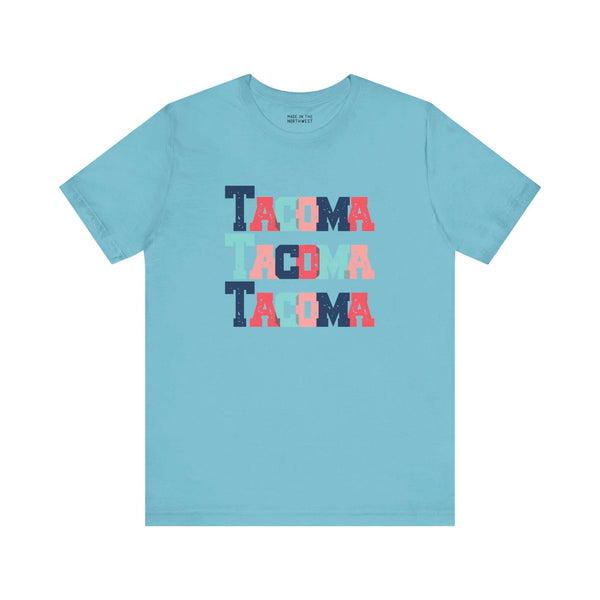 Bold and Bright Tacoma Trio Soft Tee with colorful block-letter city name design on a light blue shirt.