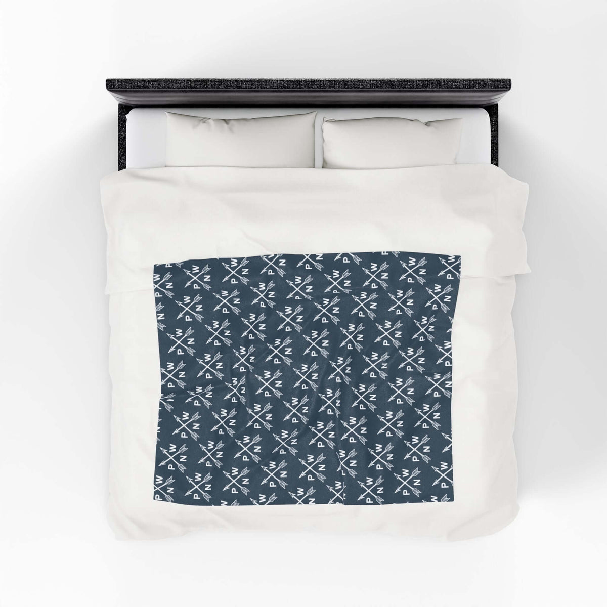 PNW Arrow Crossroads Lightweight Cozy Blanket with crossed arrows design on a bed.