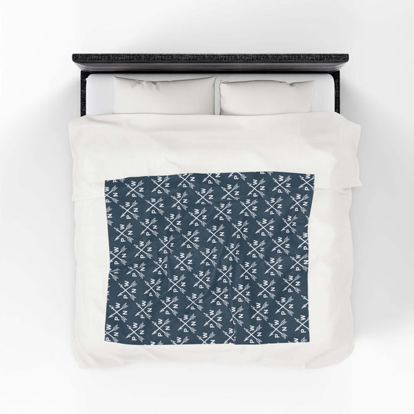 PNW Arrow Crossroads Lightweight Cozy Blanket with crossed arrows design on a bed.