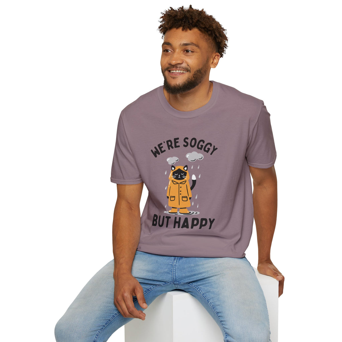 Man wearing a 'We're Soggy But Happy' t-shirt featuring a drenched cat in a raincoat, ideal for Pacific Northwest lovers.