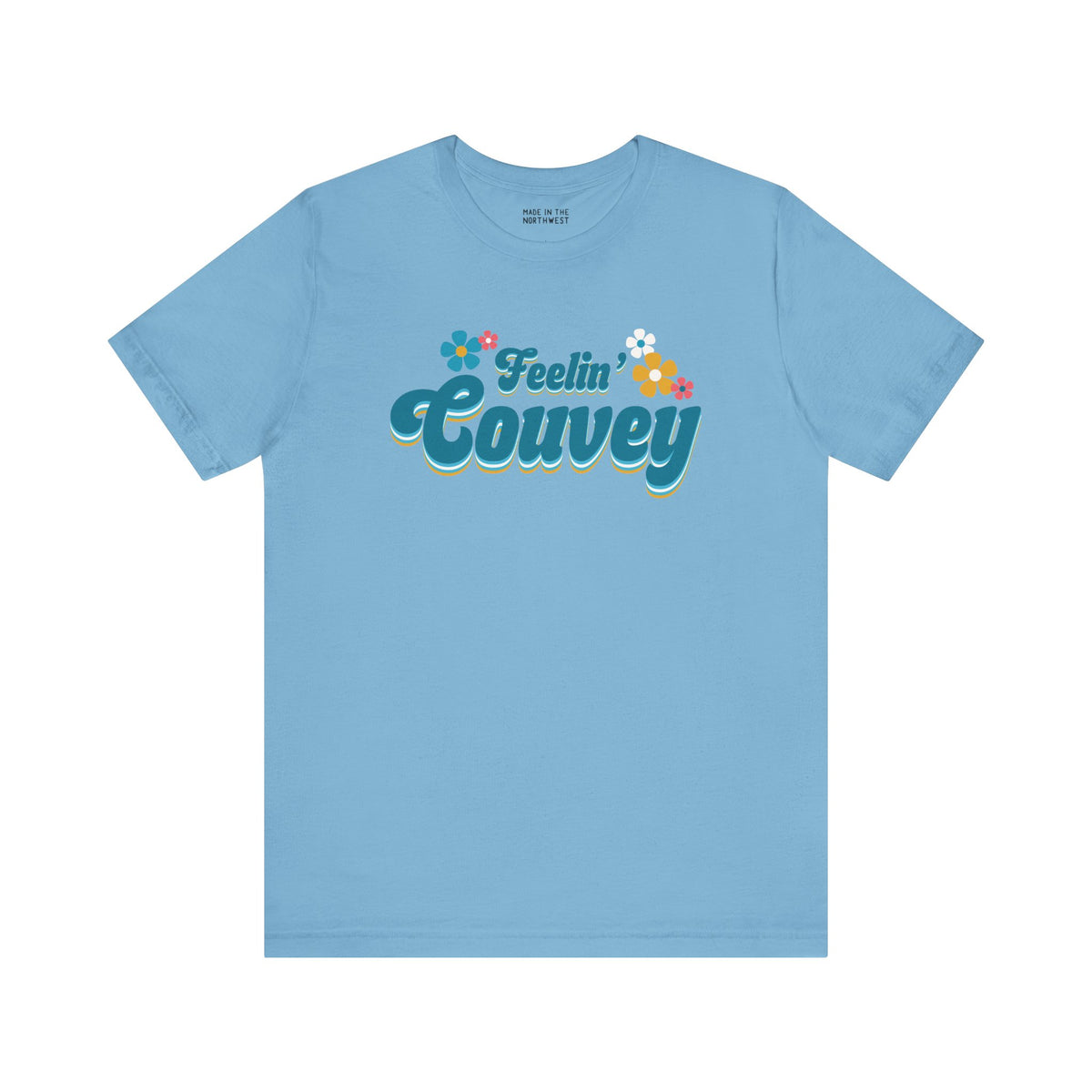 Feelin' Couvey retro soft tee in light blue featuring colorful 70s-inspired flowers and playful text design.