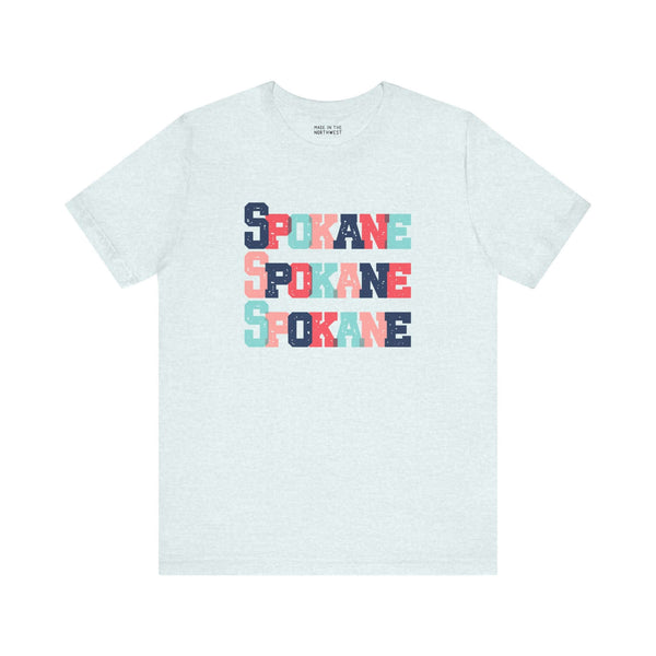 Bold and colorful Spokane trio design tee with stacked block letters on a soft fabric, perfect for Lilac City enthusiasts.