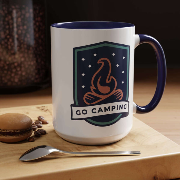 Go Camping Coffee Mug with campfire design and colorful handle on a wooden table with macaron and spoon.