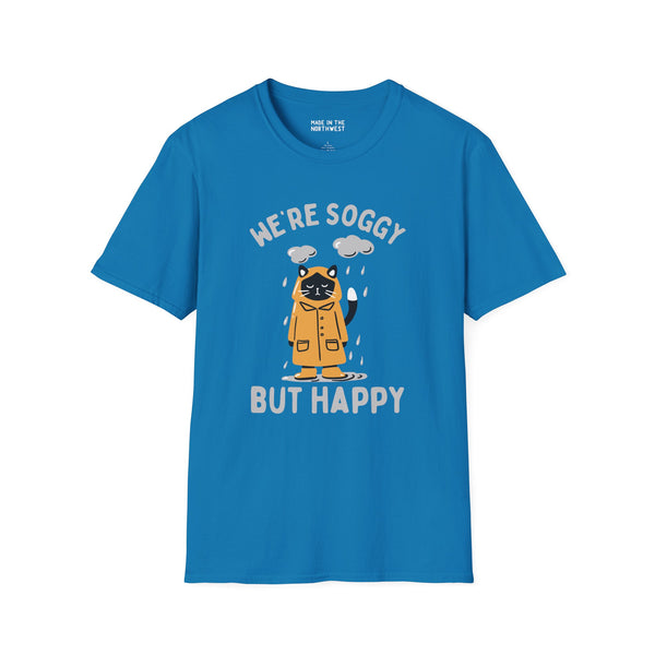 Blue t-shirt featuring a drenched cat in a raincoat with the text 'We're Soggy But Happy', perfect for Pacific Northwest lovers.
