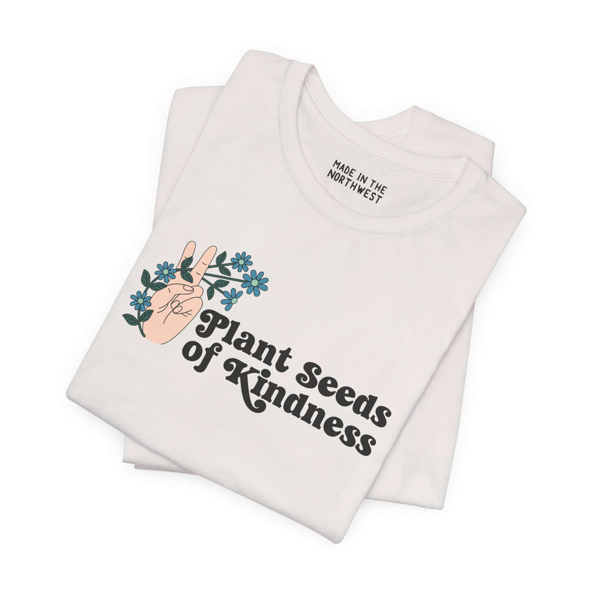 Plant Seeds of Kindness Premium Soft Tee featuring a peace sign hand and blooming flowers on a white shirt.