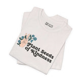 Plant Seeds of Kindness Premium Soft Tee featuring a peace sign hand and blooming flowers on a white shirt.