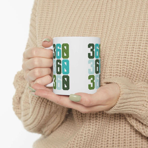 Person holding a Three-Six-Oh Pop ceramic mug featuring vibrant 360 design, embodying PNW pride.