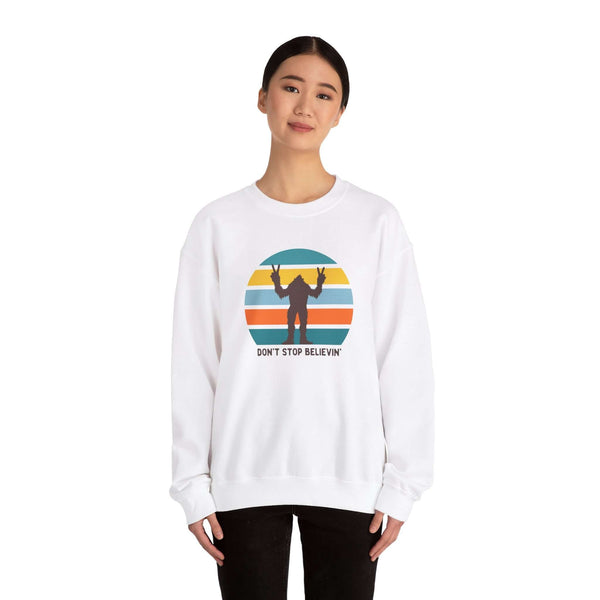 Woman wearing a white sweatshirt with a Bigfoot graphic and 'Don't Stop Believin'' text, embodying Pacific Northwest folklore.