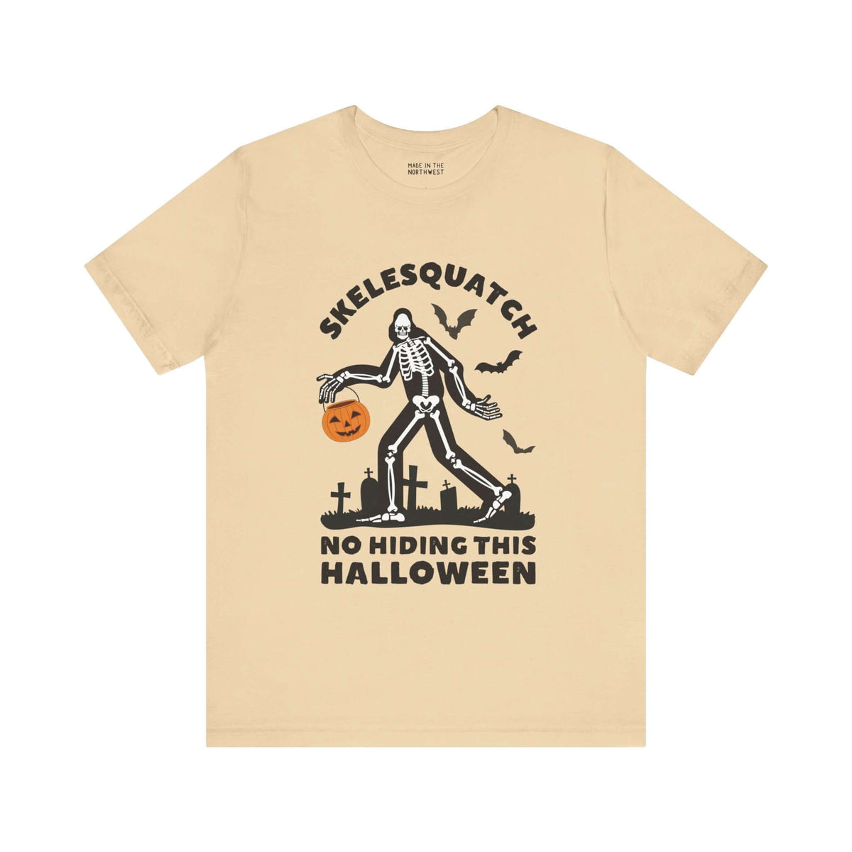 Skelesquatch Halloween tee with skeleton Sasquatch, pumpkin bucket, and graveyard design, perfect for spooky celebrations.