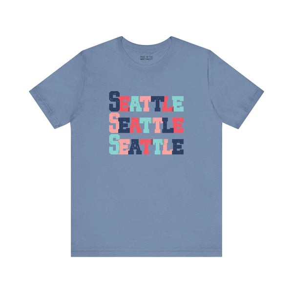 Bold and bright Seattle trio soft tee with colorful block-letter design on a blue shirt, perfect for fans of Emerald City.