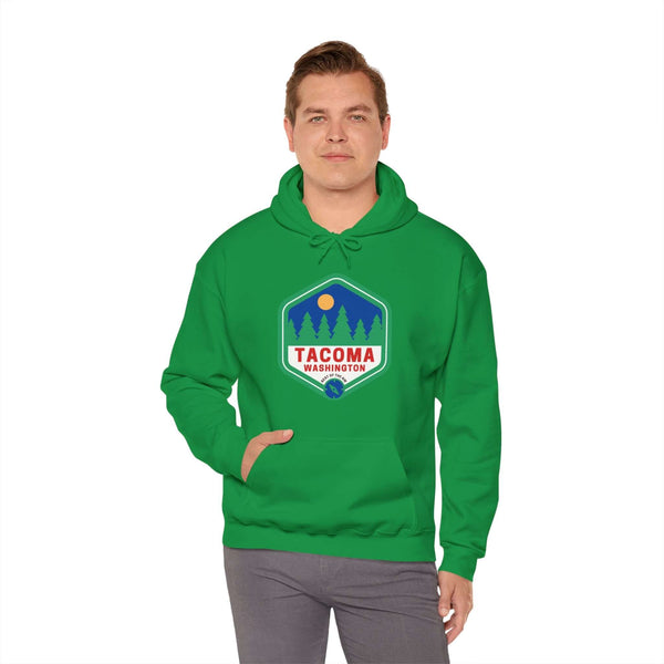 Man wearing green Tacoma hoodie with retro 90s badge featuring trees, showcasing Grit City pride and Northwest charm.