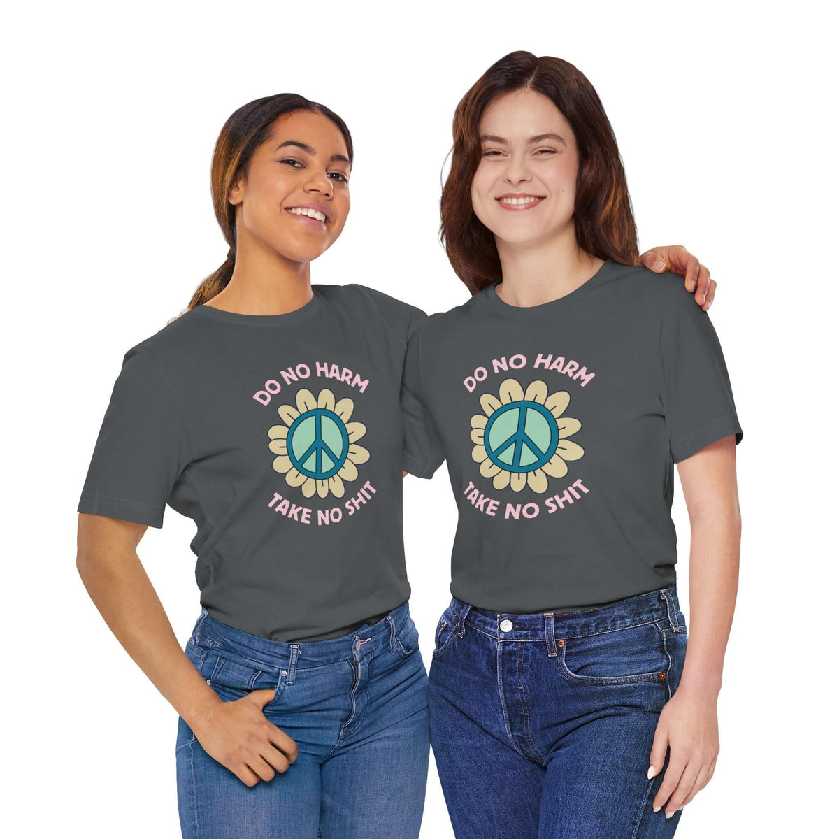 Two women wearing the Do No Harm Take No Shit Tee featuring a peace flower design.