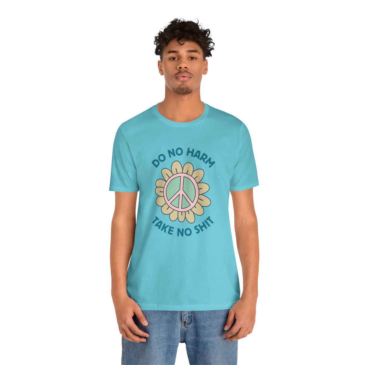 Model wearing a soft tee displaying a peace flower and the phrase 'Do No Harm, Take No Shit' in vibrant colors.
