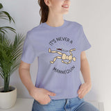 A woman wearing a light blue tee featuring the phrase 'It's Never a Mannequin' with a graphic of a posed mannequin.
