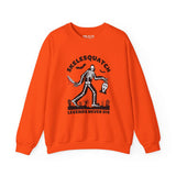 Skelesquatch Legends Never Die Halloween sweatshirt with skeleton sasquatch in graveyard, holding bloody knife and Scream mask on orange fabric.