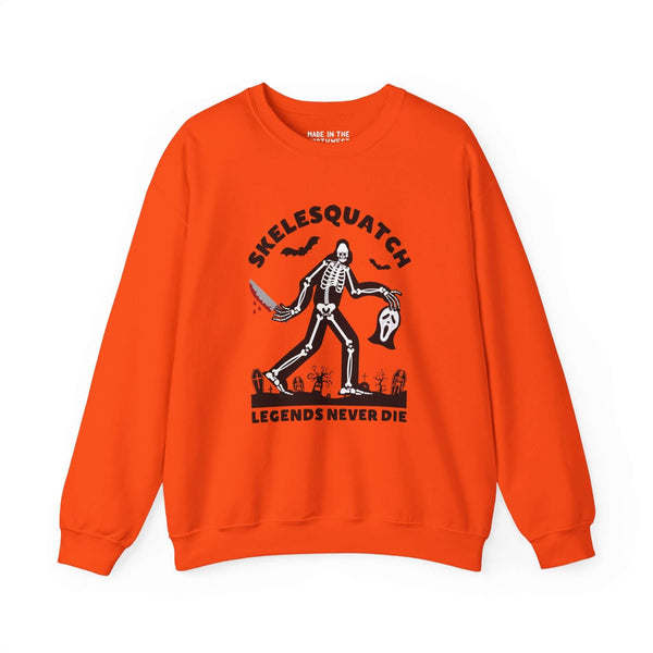 Skelesquatch Legends Never Die Halloween sweatshirt with skeleton sasquatch in graveyard, holding bloody knife and Scream mask on orange fabric.