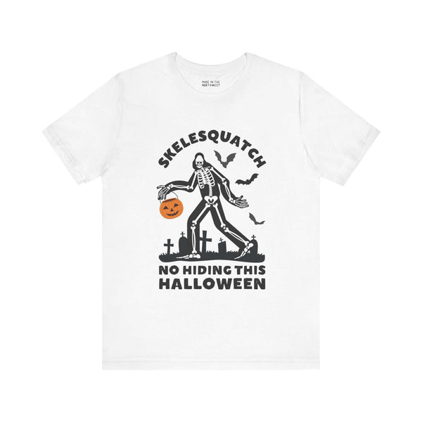 "Skelesquatch Halloween Tee featuring skeleton Sasquatch in a graveyard with pumpkin bucket and bats, perfect for spooky season"