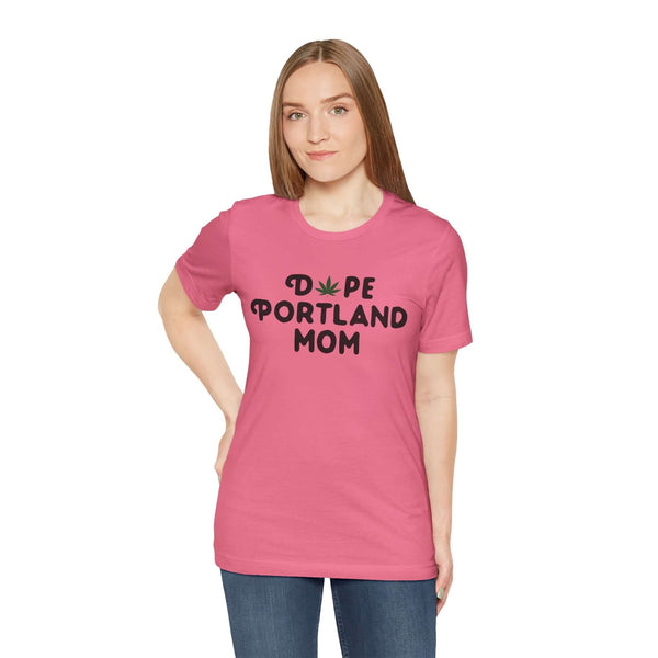 Woman wearing pink 'Dope Portland Mom' tee with marijuana leaf detail, showcasing a casual style celebrating Portland and motherhood.