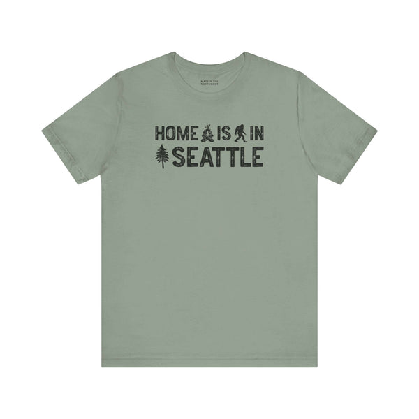 Home Is in Seattle Tee featuring campfire, Bigfoot, and tree designs showcasing Emerald City pride.