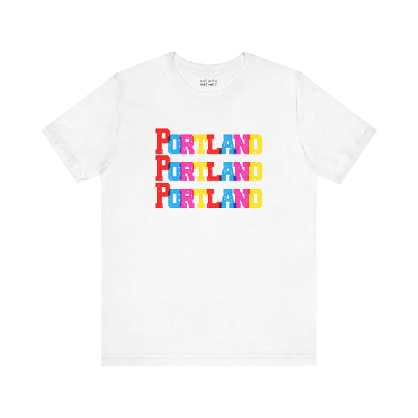 Bold Portland Trio Soft Tee with colorful block letters design on a white shirt. Perfect for Rose City fans and vibrant fashion lovers.