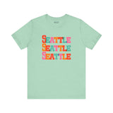 Bold and Bright Seattle Trio Soft Tee with colorful block-letter design on a mint green background.