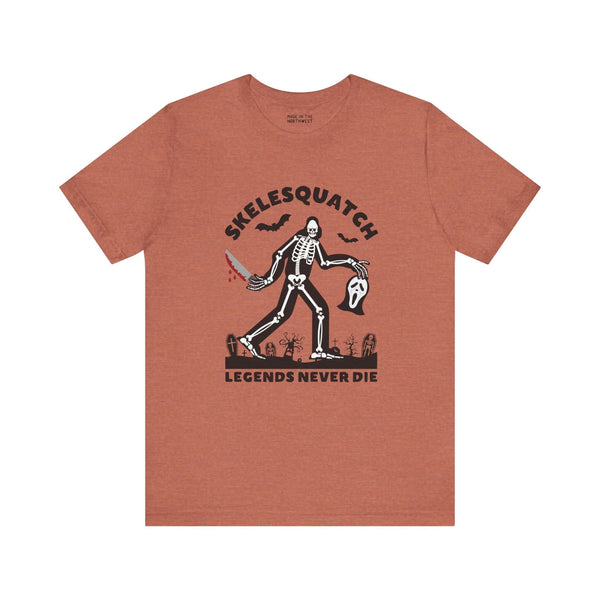 Skelesquatch Halloween soft tee featuring a skeleton sasquatch with a knife and mask, perfect for horror and cryptid fans.