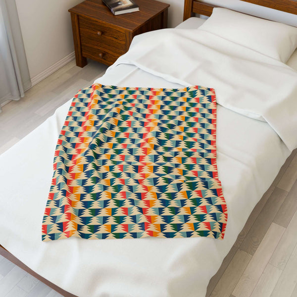 Apres Evergreen in the PNW Retro Lightweight Cozy Blanket on a bed, showcasing colorful pine tree design.