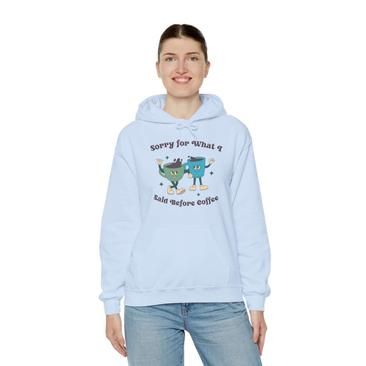 Person wearing a "Sorry for What I Said Before Coffee" hoodie, light blue color, with playful cartoon design.