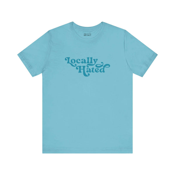 Light blue "Locally Hated" tee with bold cursive font, designed for a striking statement in the Pacific Northwest.