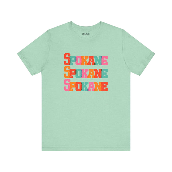 Bold and vibrant Spokane Trio Soft Tee with colorful block-letter design on a mint green shirt, perfect for Lilac City fans.