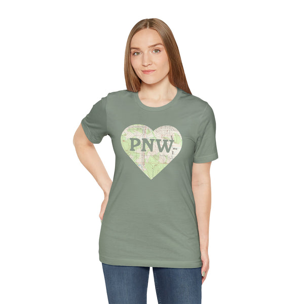 Model wearing PNW Explorer's Heart Premium Soft Tee featuring a topo map heart and bold 'PNW' design.