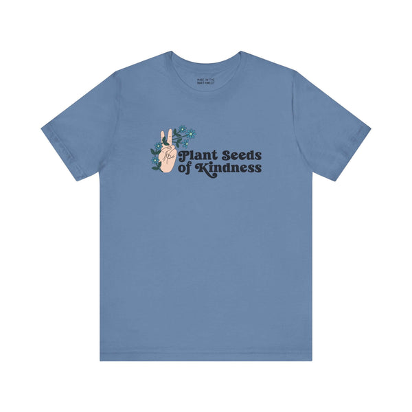 Blue tee featuring 'Plant Seeds of Kindness' with peace sign and floral design, promoting positivity and love.
