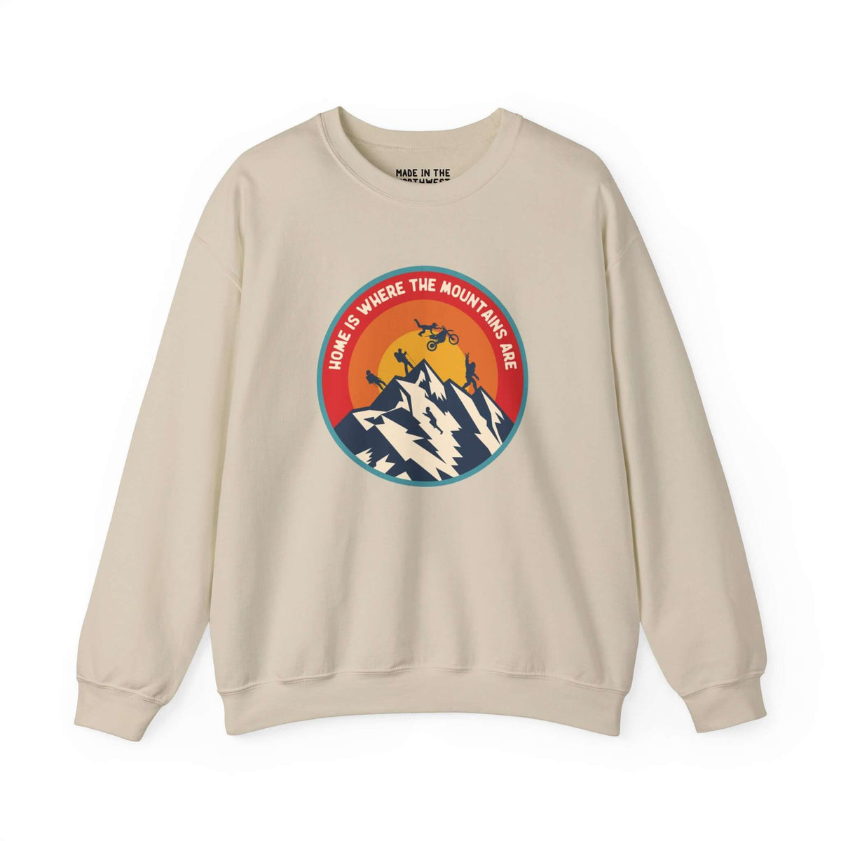 Beige sweatshirt featuring a colorful design with mountains, motocross, Bigfoot, and the text "Home is Where the Mountains Are".