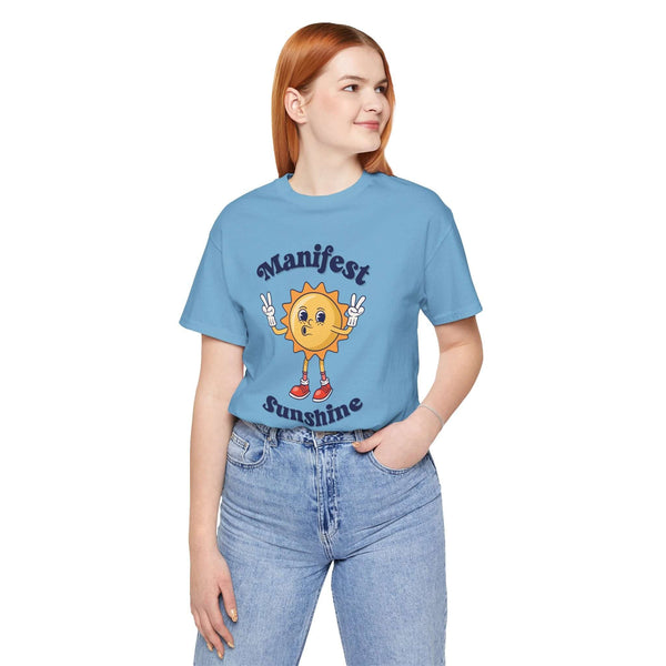 Woman wearing a blue tee with cartoon sun and text 'Manifest Sunshine' for positive vibes every day.