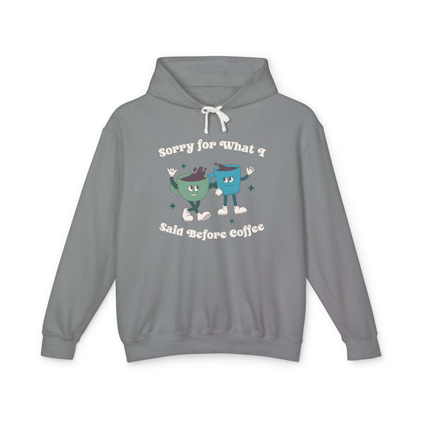 Light gray hoodie with playful text 'Sorry for What I Said Before Coffee' and cartoon coffee cups design.