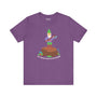 Purple soft tee featuring a gnome with an axe, saying 'Say hello to my little friend' on a stump.
