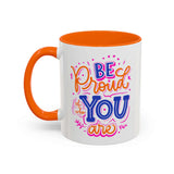 Be Proud of Who You Are mug with colorful hand-lettered design and orange interior.