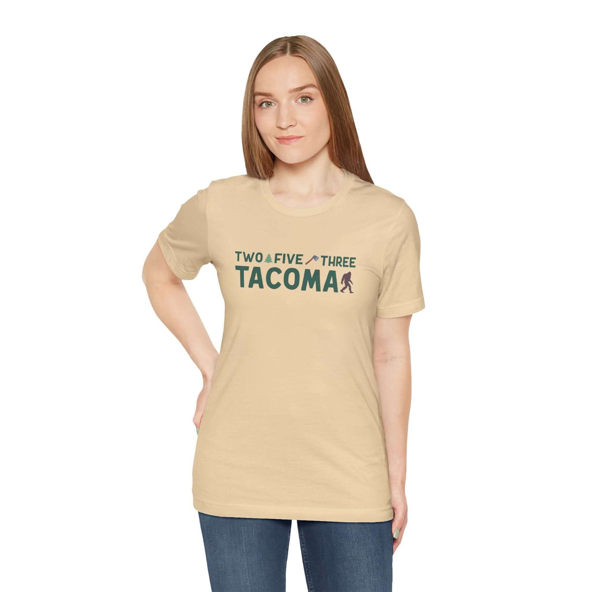 Woman wearing beige Tacoma "Two Five Three" tee with axe and tree design, celebrating local pride and style.