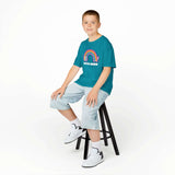Boy wearing Love Wins Rainbow kids' tee with a cat and rainbow design, spreading joy and kindness.