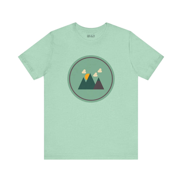 Minimalist forest-themed soft tee in northwest style with simple mountain graphic on a light green background. Perfect for nature lovers.