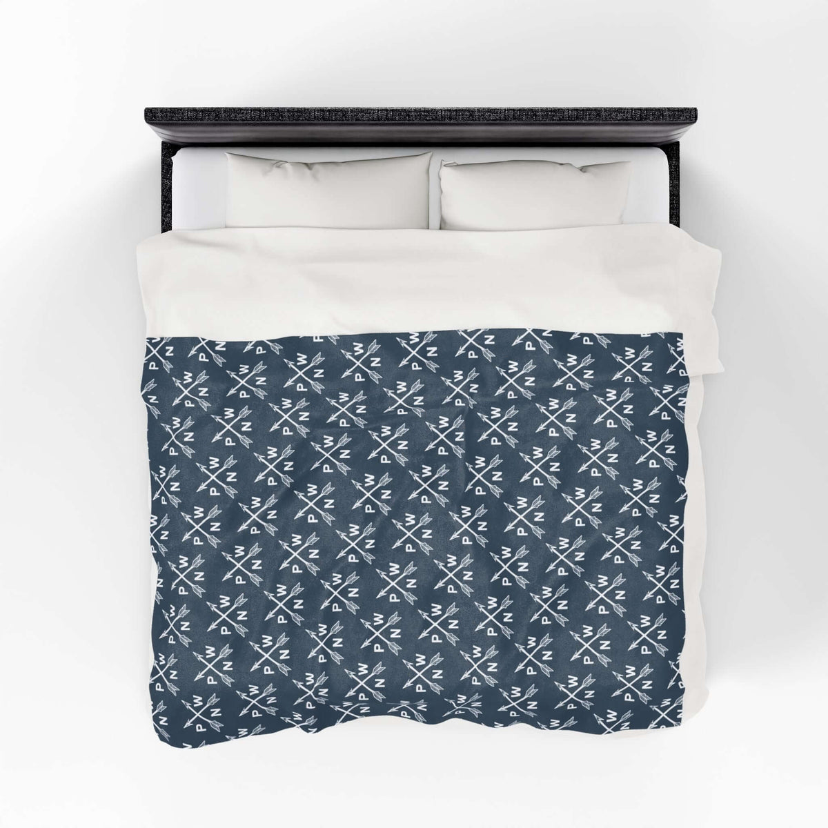 PNW Arrow Crossroads Lightweight Cozy Blanket on a bed, featuring a stylish crossed arrows design.