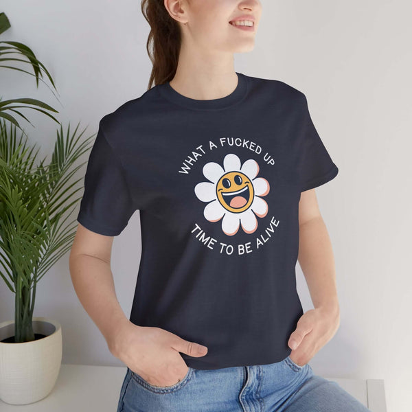 Cheerful woman wearing 'What a F*cked Up Time to Be Alive' graphic tee with a smiling daisy design.