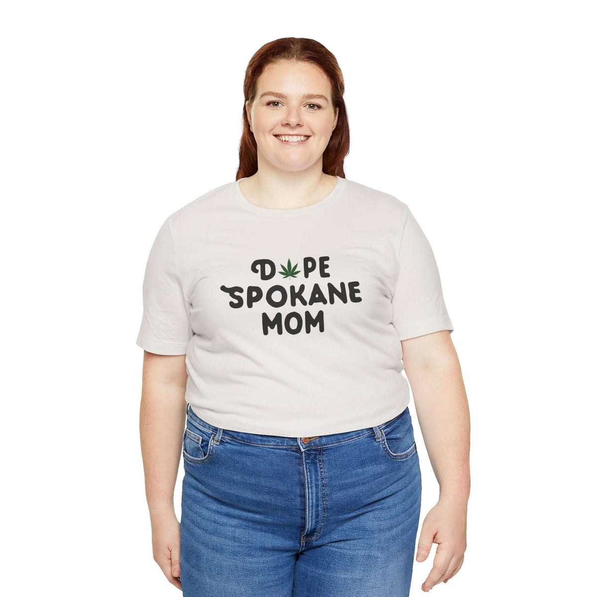 Woman wearing a white 'Dope Spokane Mom' tee with marijuana leaf in place of 'O', showcasing unique style.