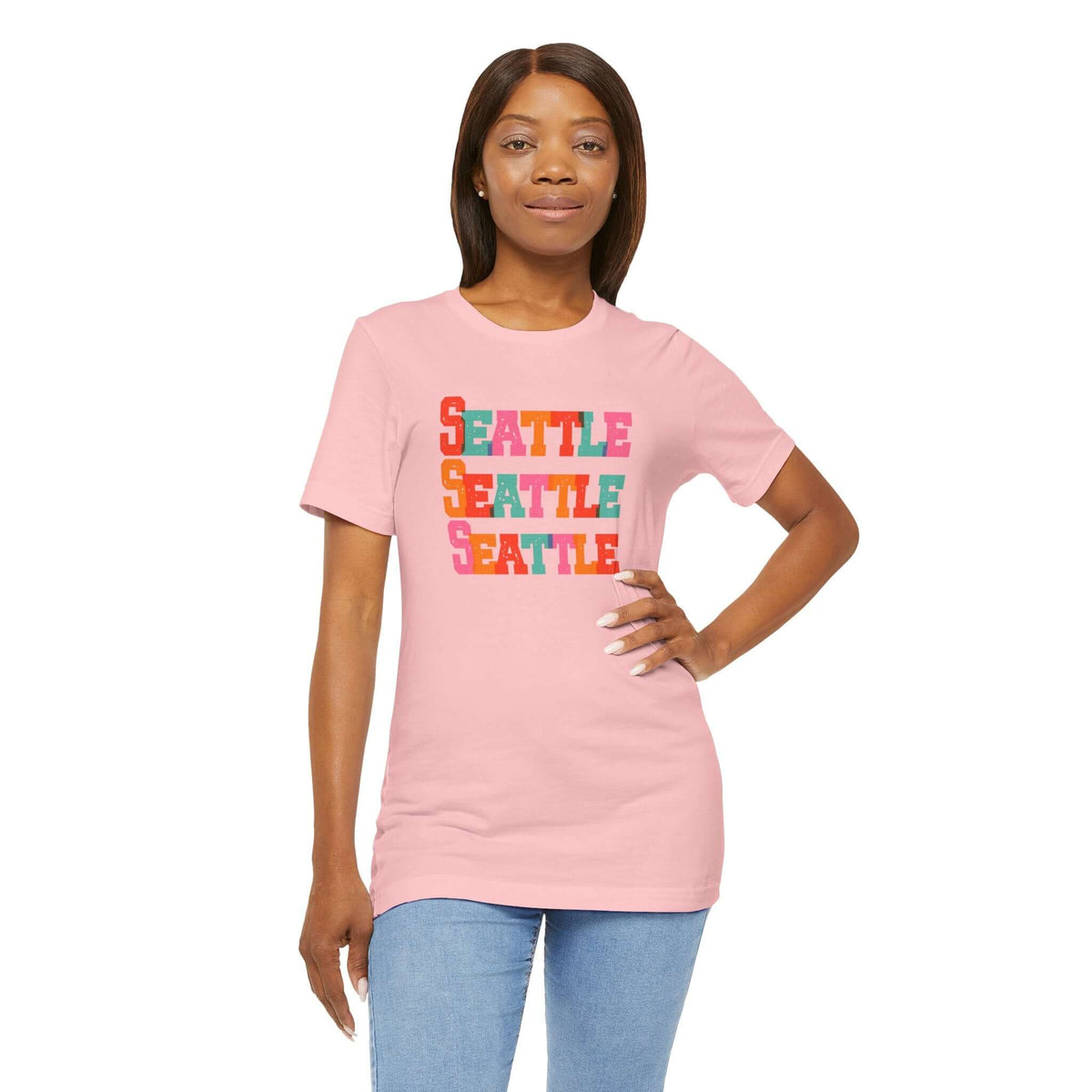 Model wearing a pink Seattle tee with colorful block letters celebrating the city.