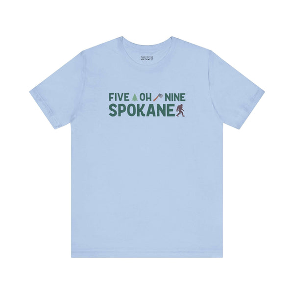 Light blue Spokane tee with "Five Oh Nine" text, featuring an axe and tree design, celebrating local pride and area code charm.