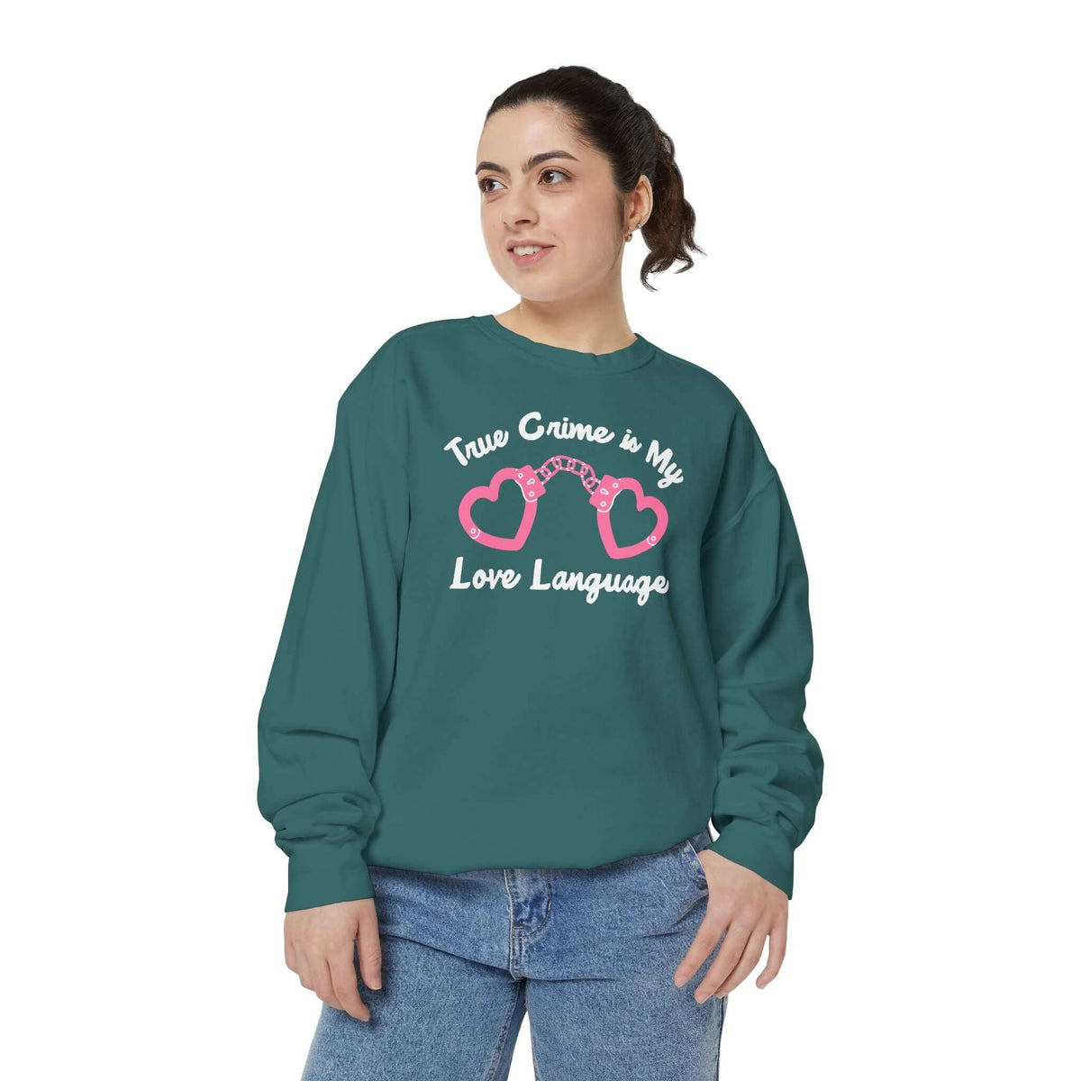 Woman wearing a teal sweatshirt with the phrase 'True Crime Is My Love Language' and heart-shaped handcuffs design.
