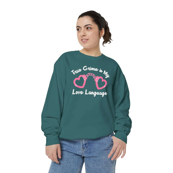 Woman wearing a teal sweatshirt with the phrase 'True Crime Is My Love Language' and heart-shaped handcuffs design.