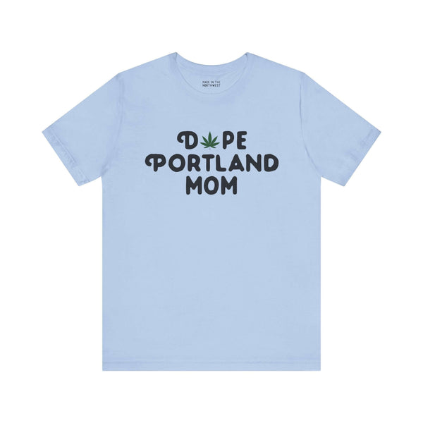 Light blue tee with "Dope Portland Mom" text featuring a marijuana leaf as the 'O', celebrating chill motherhood and PDX pride.